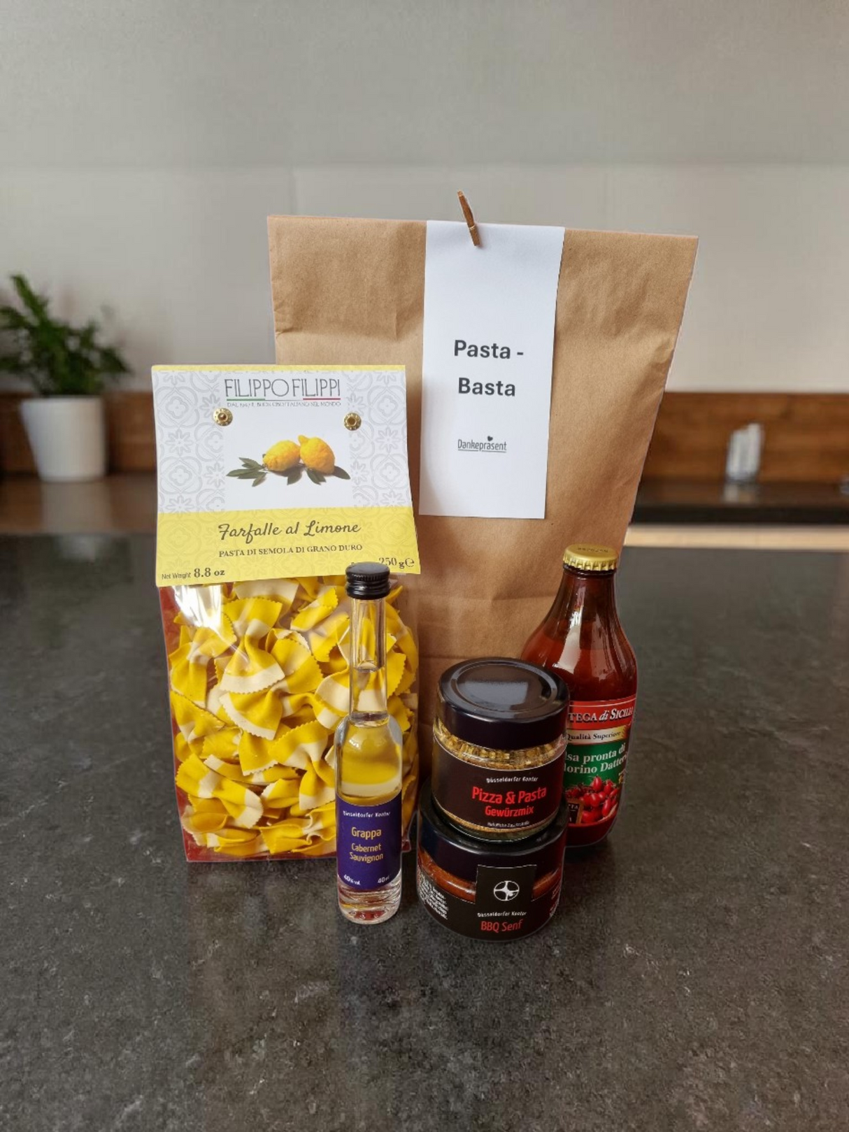 Stilvolle Wundertüte „Danke schön“ mit hochwertiger Feinkost als elegantes Geschenk, platziert auf einem eleganten Küchenblock - Dankepräsent