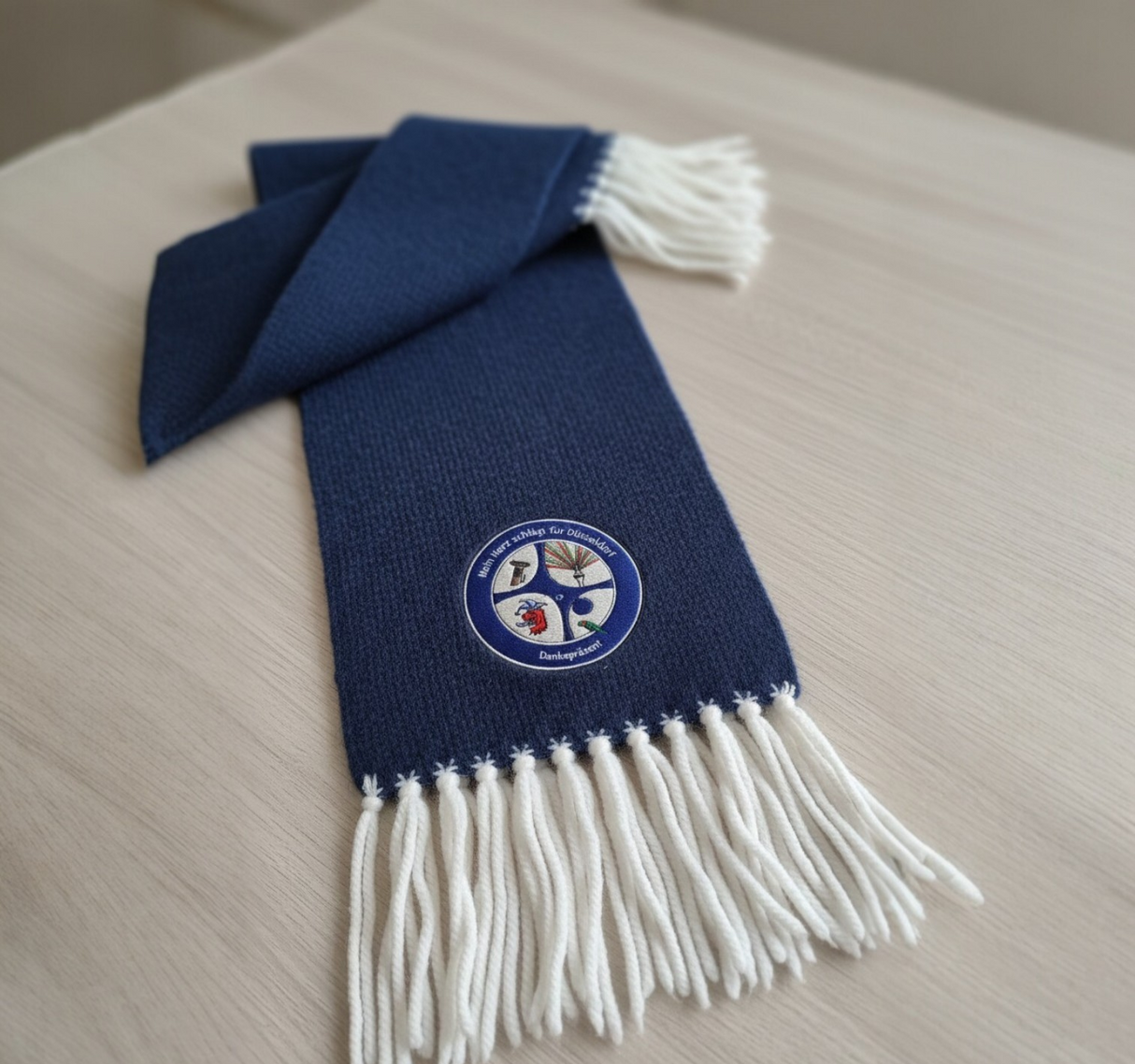 Blauer Fan-Schal mit weißen Fransen & Radschläger-Stick von Dankepräsent Düsseldorf. Hochwertige Teamkleidung & Vereinsausstattung für Unternehmen & Vereine. Individuelles Dankepräsent für Teamspirit & Branding, bundesweit mit Full-Service lieferbar.