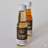 Hochwertige 20ml Spirituosen-Miniaturflaschen mit dunkelbraunem Etikett und Logo-Platzhalter auf hellem Hintergrund – personalisierte Edelbrände als Firmengeschenk von Dankepräsent.
