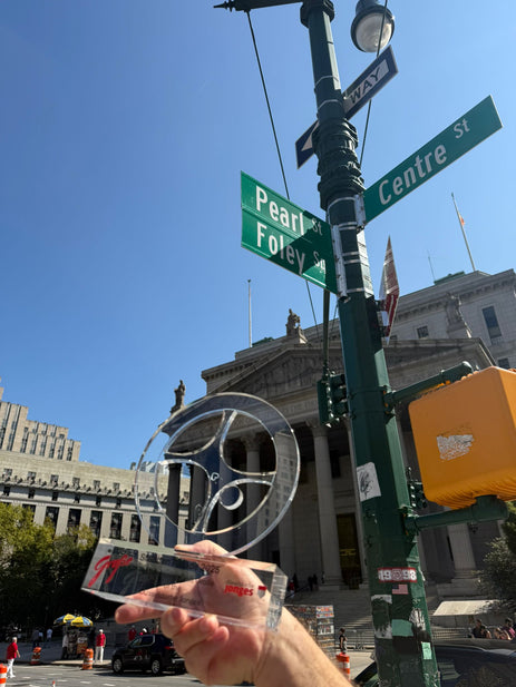 Radschläger-Skulptur wird an einer New Yorker Straßenkreuzung vor den Straßenschildern Centre St, Pearl St und Foley Sq gehalten – Symbol für Düsseldorfer Tradition bei der Steubenparade 2025.